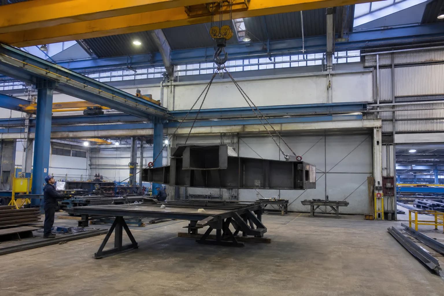Overhead crane lifting a fabricated steel assembly in a shop bay